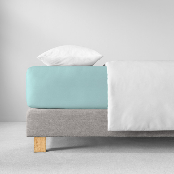 Spannbettlaken in strahlenden, türkisblauen Farbton auf Bett aufgezogen