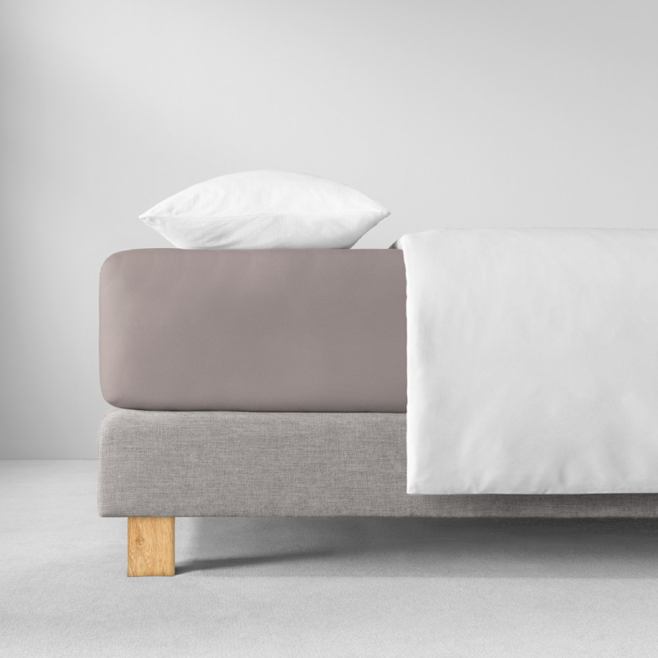 Spannbettlaken in hellen, warmen Graubraun auf Bett aufgezogen