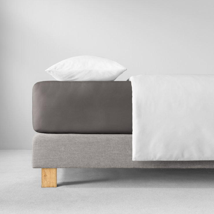 Spannbettlaken in dunklen, warmen Grau mit braunem Unterton auf Bett aufgezogen