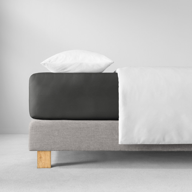 Spannbettlaken in sehr dunklen, kühlen Schwarzgrau auf Bett aufgezogen