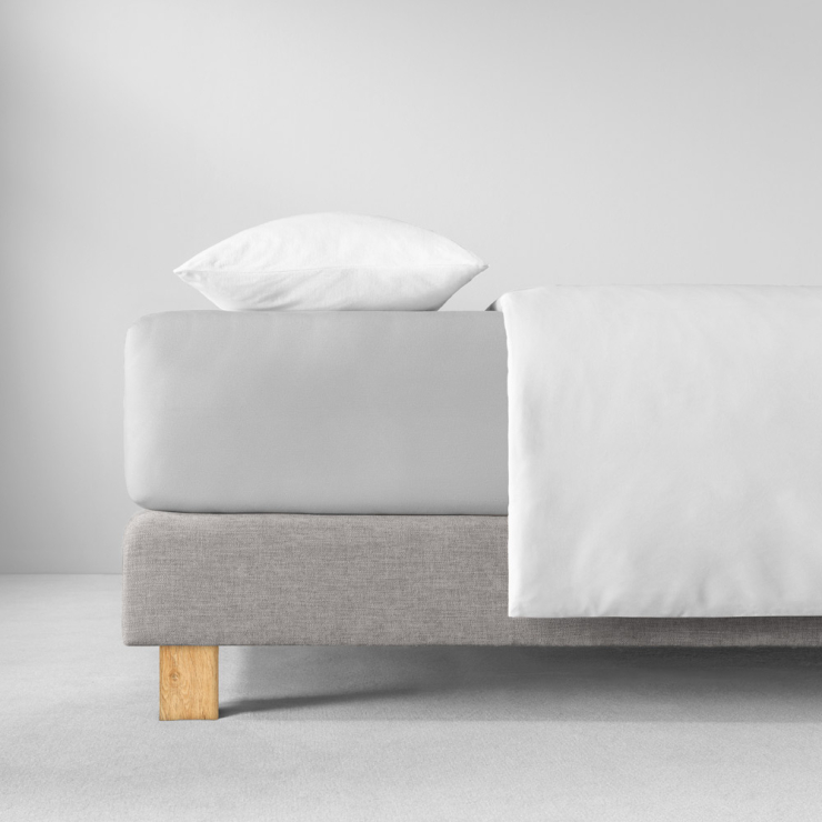 Spannbettlaken in hellen, kühlen Neutralgrau auf Bett aufgezogen