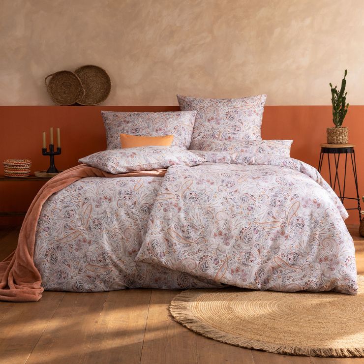 Bettwäsche Nikola mit Paisley-Muster in Rosa und Beige auf weißem Grund auf Bett im Schlafzimmer
