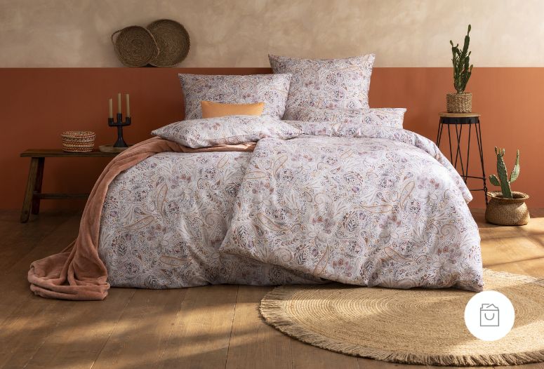 Bettwäsche Nikola mit feinem Paisley-Muster aus geschwungenen Ornamenten und floralen Details in zarten Rosé-, Beige- und Grautönen auf Bett im Schlafzimmer