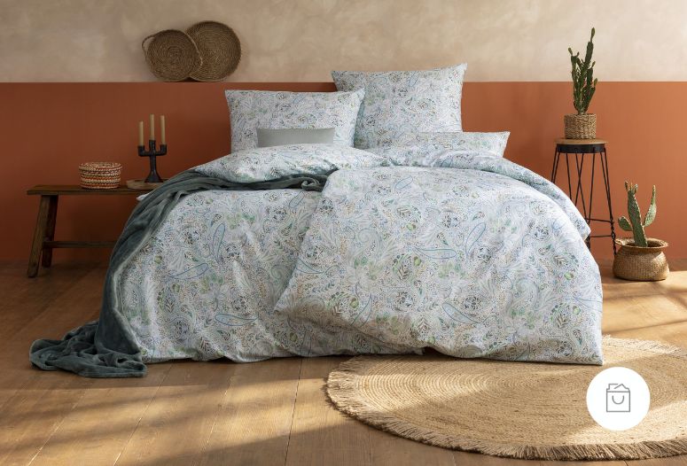 Bettwäsche Nikola mit feinem Paisley-Muster aus geschwungenen Ornamenten und floralen Details in sanften Grün-, Blau- und Beigetönen auf Bett im Schlafzimmer