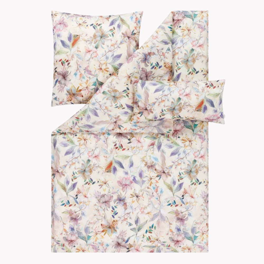 Bettwäsche Estera mit floralem Muster in Rosa und Blau auf beigem Grund auf Bett im Schlafzimmer
