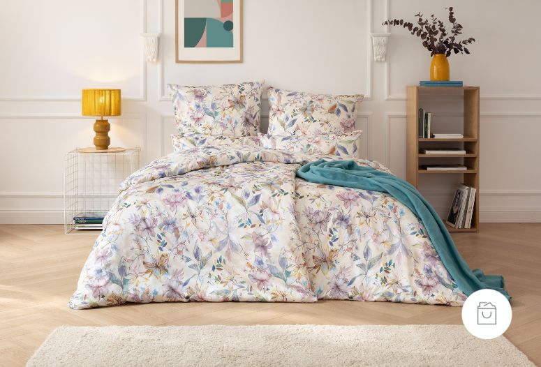 Bettwäsche Estera mit florales Muster in Lila und Grün auf beigem Grund auf Bett im Schlafzimmer