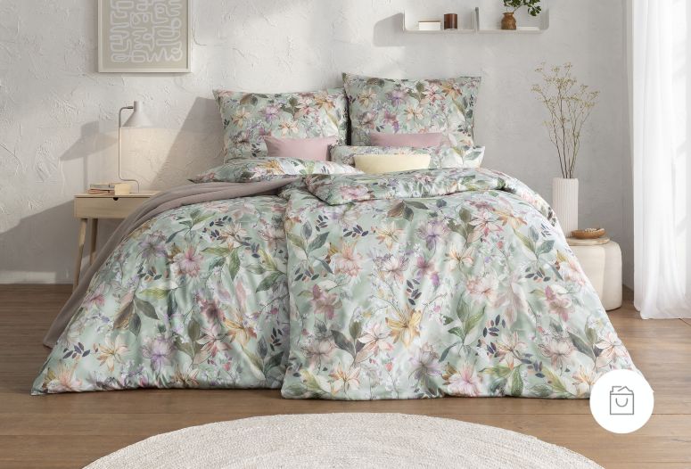 Bettwäsche aus Mako-Satin mit zartem Blumenmuster in Pastellfarben auf mintgrünem Grund – romantisch arrangiert im hellen Schlafzimmer. - Demnächst verfügbar
