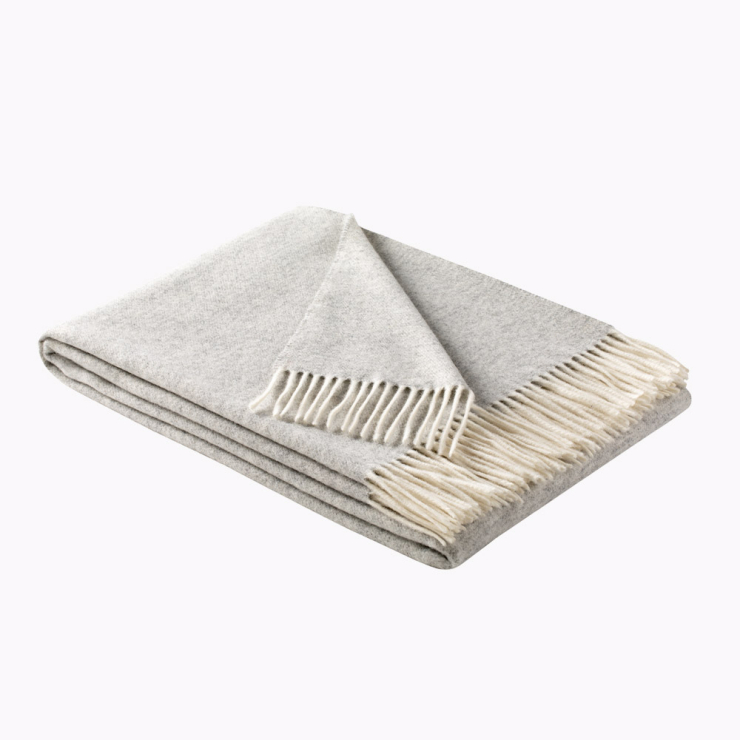 Gefaltete Wohndecke in Silber, ein heller Grauton mit Fransen in Cremeweiß