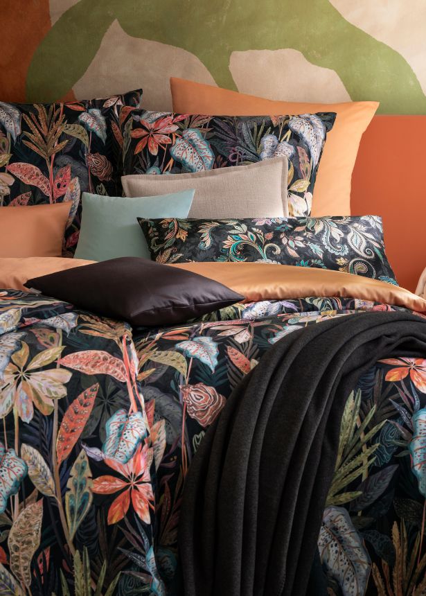 Bettwäsche Juliane mit floralem Blattmuster in bunten Naturtönen kombiniert mit Uni Bettwäsche Valetta in Orange/Apricot, dekoriert mit verschiedenen Dekokissenbezügen und dunkler Wohndecke auf Doppelbett in stilvollem Schlafzimmer