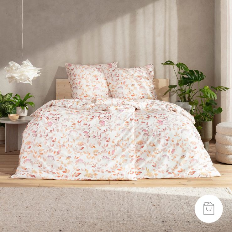 Bettwäsche Beatriz mit Blüten und Blättern in Rosa und Beige auf weißem Grund auf Bett im Schlafzimmer