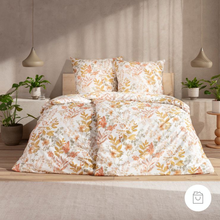 Bettwäsche Flor mit Blüten und Blättern in Gelb und Orange auf weißem Grund auf Bett im Schlafzimmer