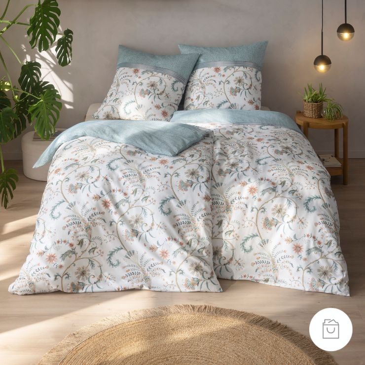 Bettwäsche Leia in der Farbe Azur mit filigranem Ornamentmuster in Azurblau, Beige und Salbeitönen auf weißem Fond, veredelt durch eine dekorative Bordüre im oberen Bereich.