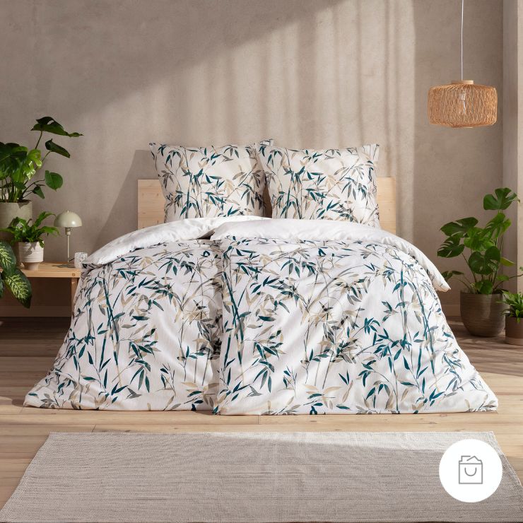 Bettwäsche Palmira mit Bambusblättern in Grün und Beige auf weißem Grund auf Bett im Schlafzimmer
