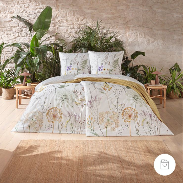 Bettwäsche Veronica mit Wiesenblumen und Gräsern in Gelb und Lila auf Weißem Grund auf Bett im Schlafzimmer