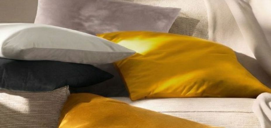 Dekokissen Velvet in honig, grau und schiefer auf Sofa und Boden in wohnlicher Umgebung