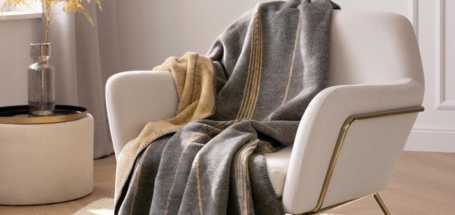 Estella Wohndecke Caja in der Farbe anthrazit gemütlich über Stuhl gelegt.