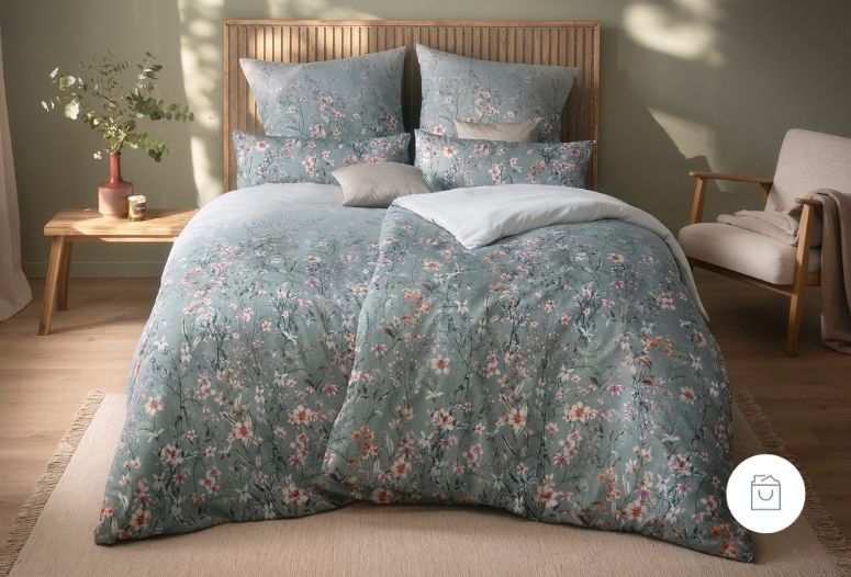 Bettwäsche Gesina mit Wiesenblumen in Weiß und Rosa auf hellblauem Grund auf Bett im Schlafzimmer