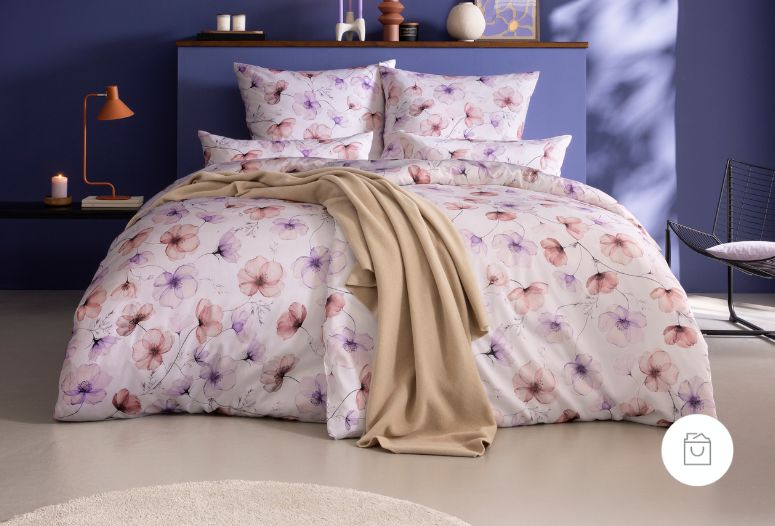 Bettwäsche Delia mit Blüten in Rosa und Lila auf hellrosa Grund auf Bett im Schlafzimmer
