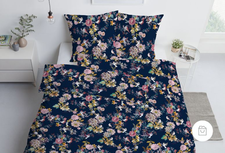 Bettwäsche Rommy mit Blüten und Vögeln in Rosa und Gelb auf dunkelblauem Grund auf Bett im Schlafzimmer