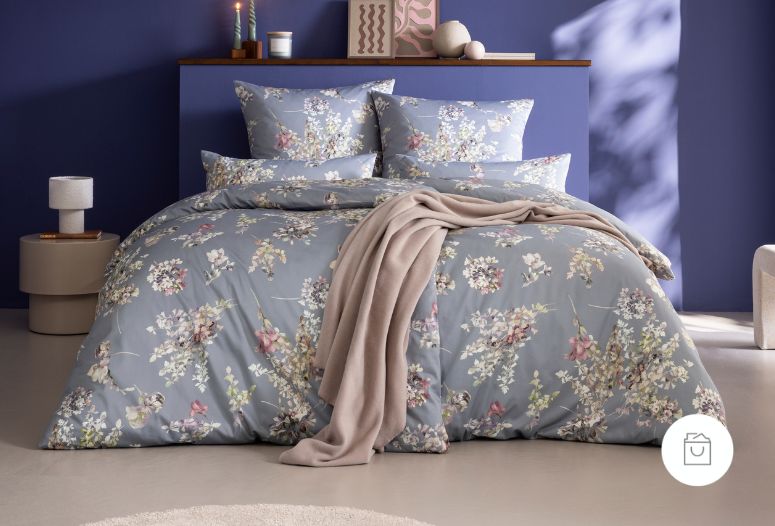 Bettwäsche Jutta mit Blüten in Weiß und Rosa auf blauem Grund auf Bett im Schlafzimmer