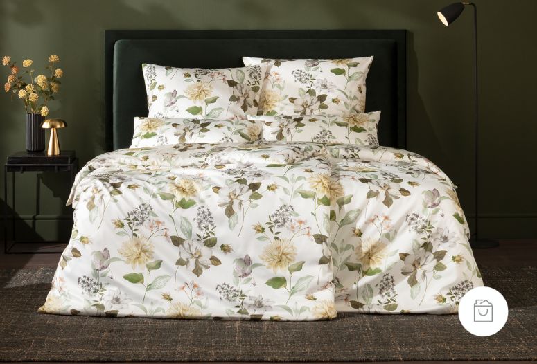 Bettwäsche Lucia mit Blüten und Blättern in Grün und Beige auf weißem Grund auf Bett im Schlafzimmer