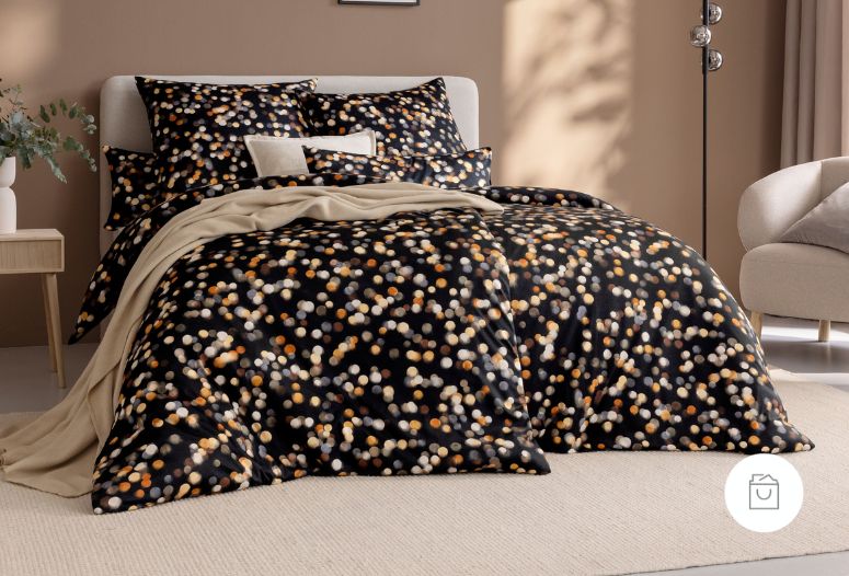 Bettwäsche Vinzenz mit Punktemuster in Beige und Orange auf schwarzem Grund auf Bett im Schlafzimmer