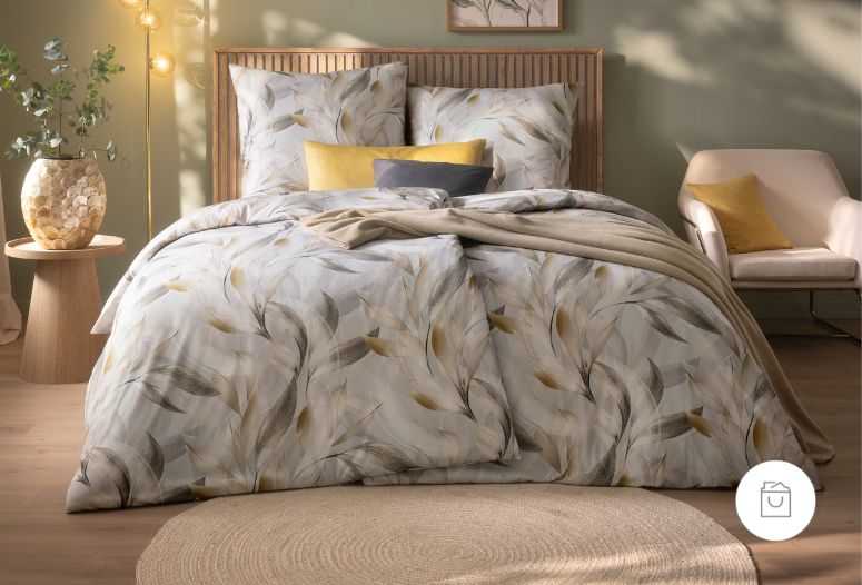 Bettwäsche Nathalie mit eleganten Blättern in Beige und Grau mit leichten goldenen Akzenten auf silbernen Grund auf Bett im Schlafzimmer